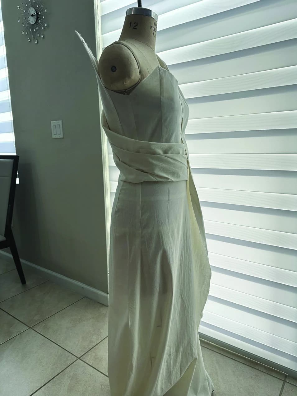 White draped Faith garment in progress on a dress form, front view.